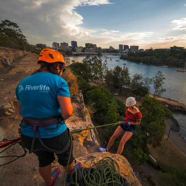 Guide belaying an abseiler descending the Kangaroo Point cliffs at dusk